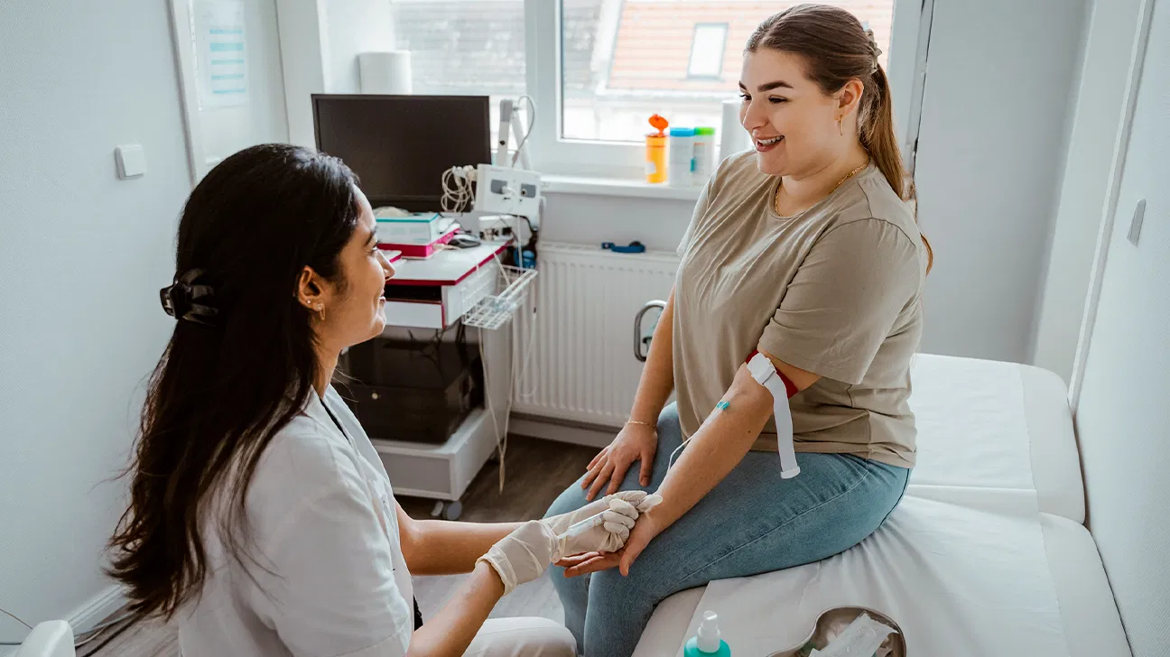 A clinician holding a blood sample tube while reviewing a lab order for a vitamin D test