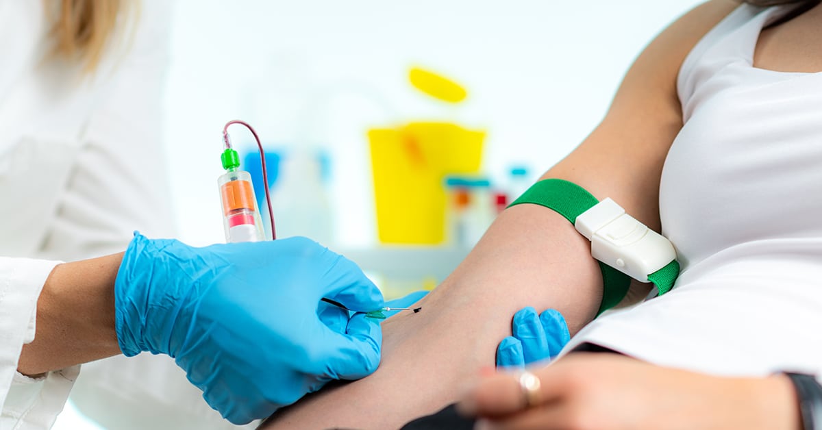 A healthcare professional holding a lab requisition while a patient sits in a clinic room, suggesting thyroid blood testing