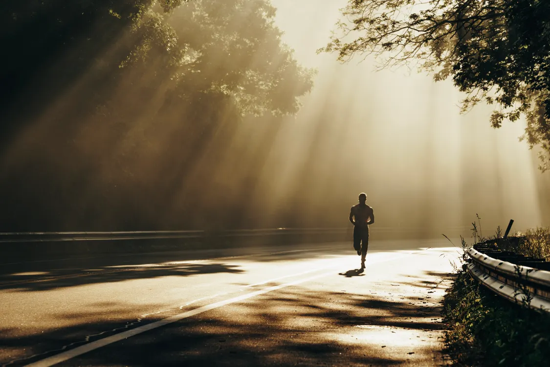 An adult walking on a neighborhood trail in daylight with forearms exposed