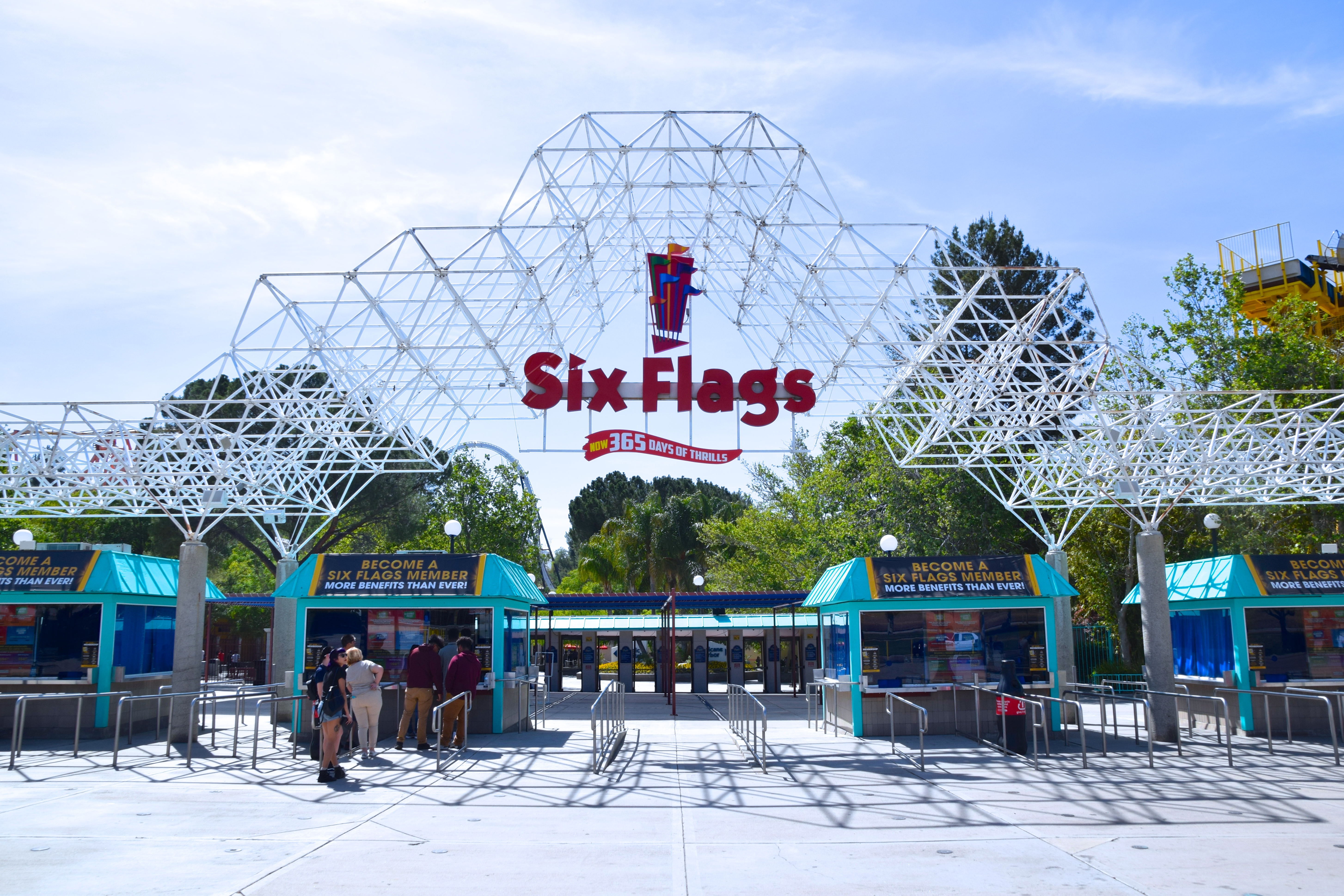 Guests walking toward the entrance gates of Six Flags Magic Mountain on a sunny day